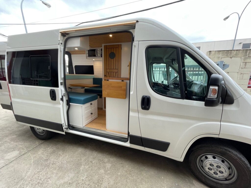 Detalhe da furgoneta Boxer L2H2 3+3 com porta lateral aberta, acabamento interno em branco e madeira