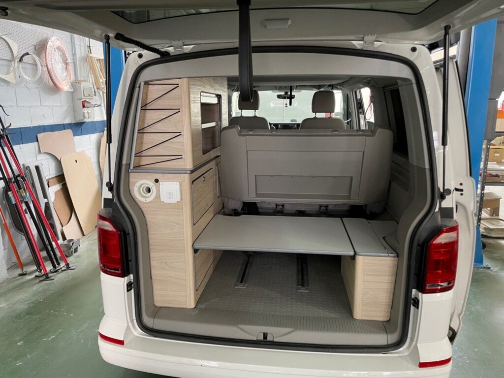 Vista trasera de una Camper California T6 mostrando una cama plegable
