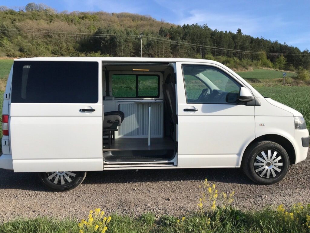 [Furgoneta camper blanca en la naturaleza, puerta lateral abierta