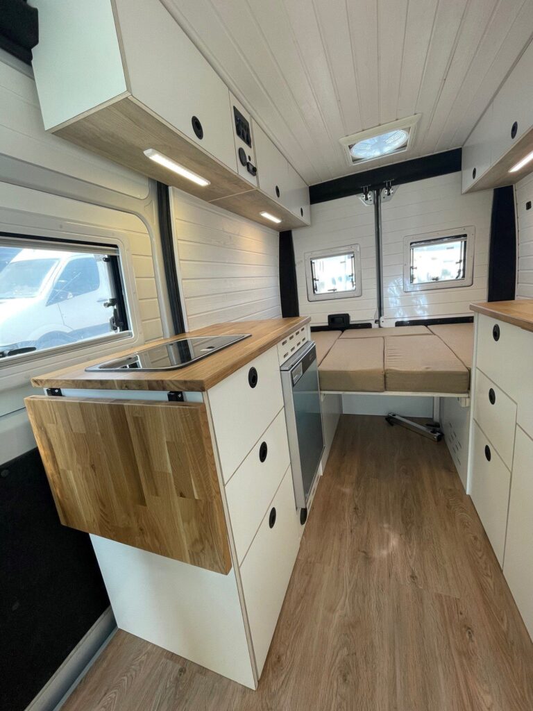 Interior de la Camper Fiat Ducato L2H2 de Baovan Camper, ideal para 2 personas, con un diseño inteligente para maximizar el aprovechamiento del espacio. Estilo moderno con suelo de vinilo, armarios funcionales y cocina completa, asegurando confort y practicidad en tus aventuras.