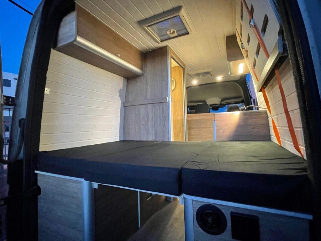 Detalle desde la puerta trasera: cama montada, amplia, espacio de almacenamiento, Camperizado por BaovanCamper