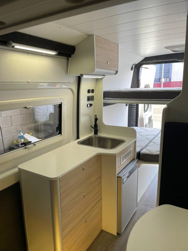 Detalle interno de la cocina: fregadero, ventana, nevera, espacio para guardar cosas, Camperizado por Baovan Camper