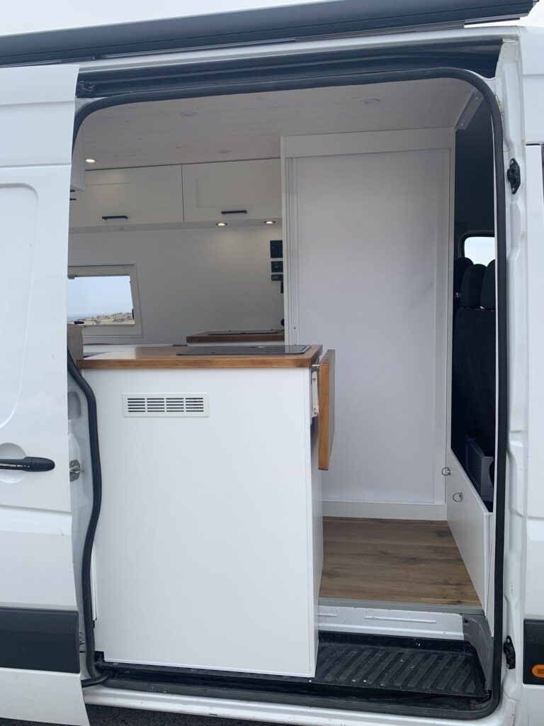 Vista desde fuera del balcón del fregadero, blanco y amadeirado, en la Camper Mercedes Sprinter L3H2 4+4. Camperizado por BaovanCamper.