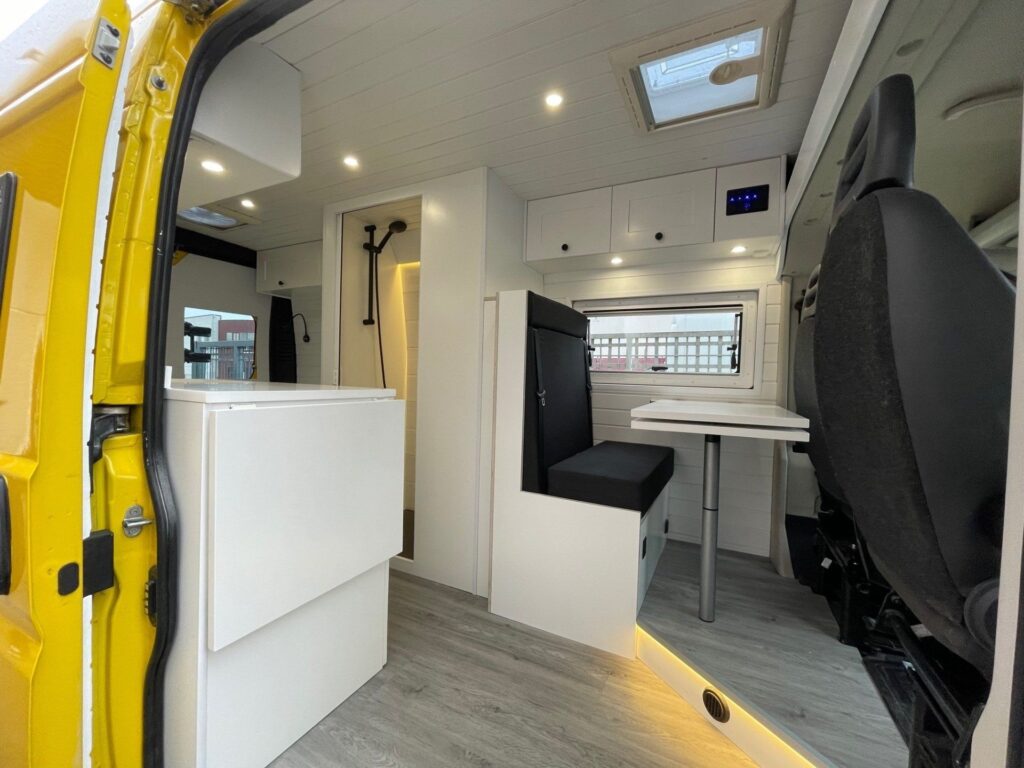 Vista con la puerta abierta: bancos delanteros, zona de descanso, Camperización por Baovan Camper