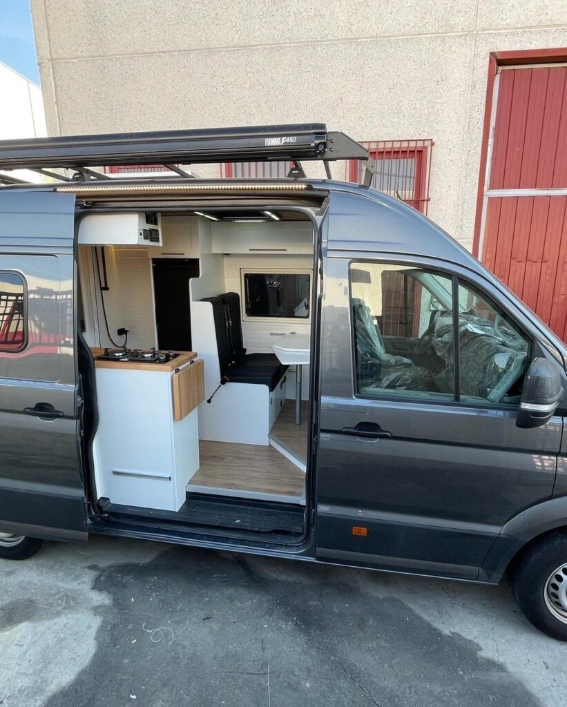 Puerta lateral abierta de la VW Crafter L2H2 2+2 mostrando el interior.