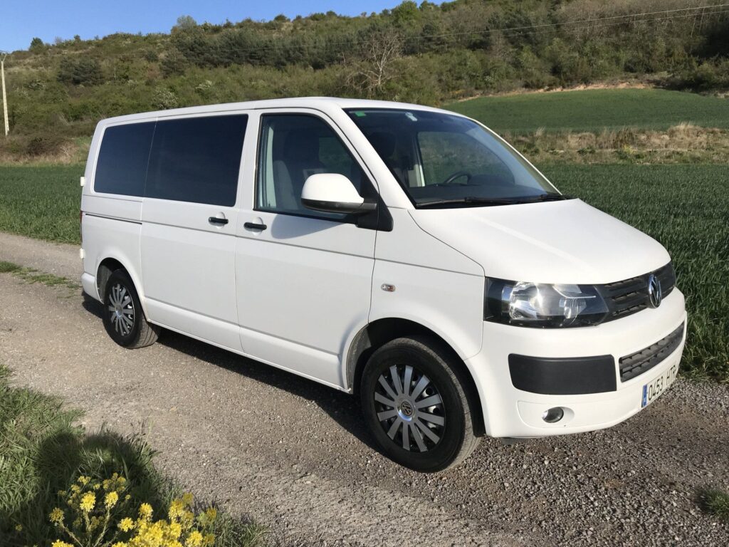 Furgoneta camper Volkswagen Transporter T5 blanca, todas las puertas cerradas, espacio florido