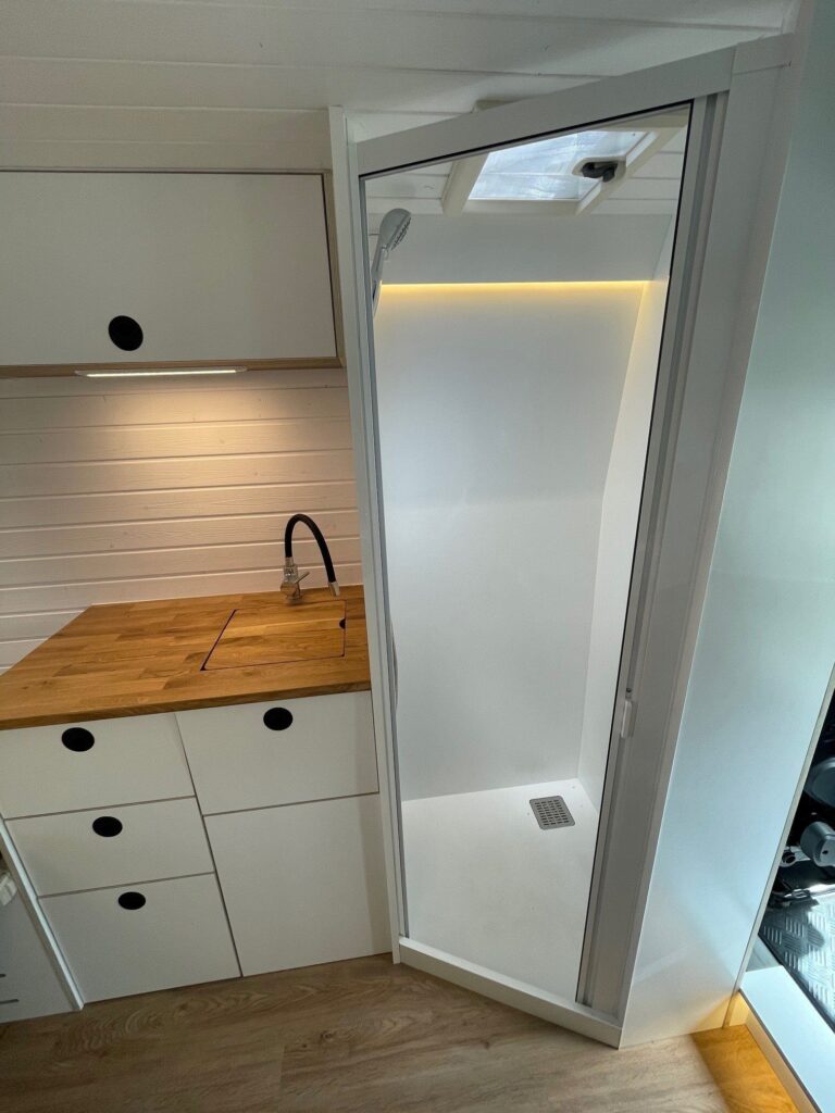Interior de la camperización Baovan en una Fiat Ducato L2H2, destacando la ducha compacta.