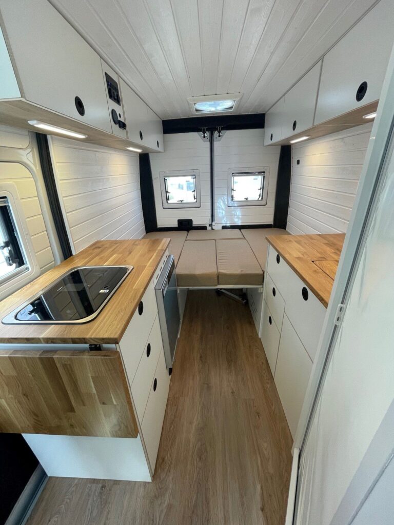 Espacio interno de la Fiat Ducato L2H2 camperizada por Baovan, mostrando la cocina y cama para dos.