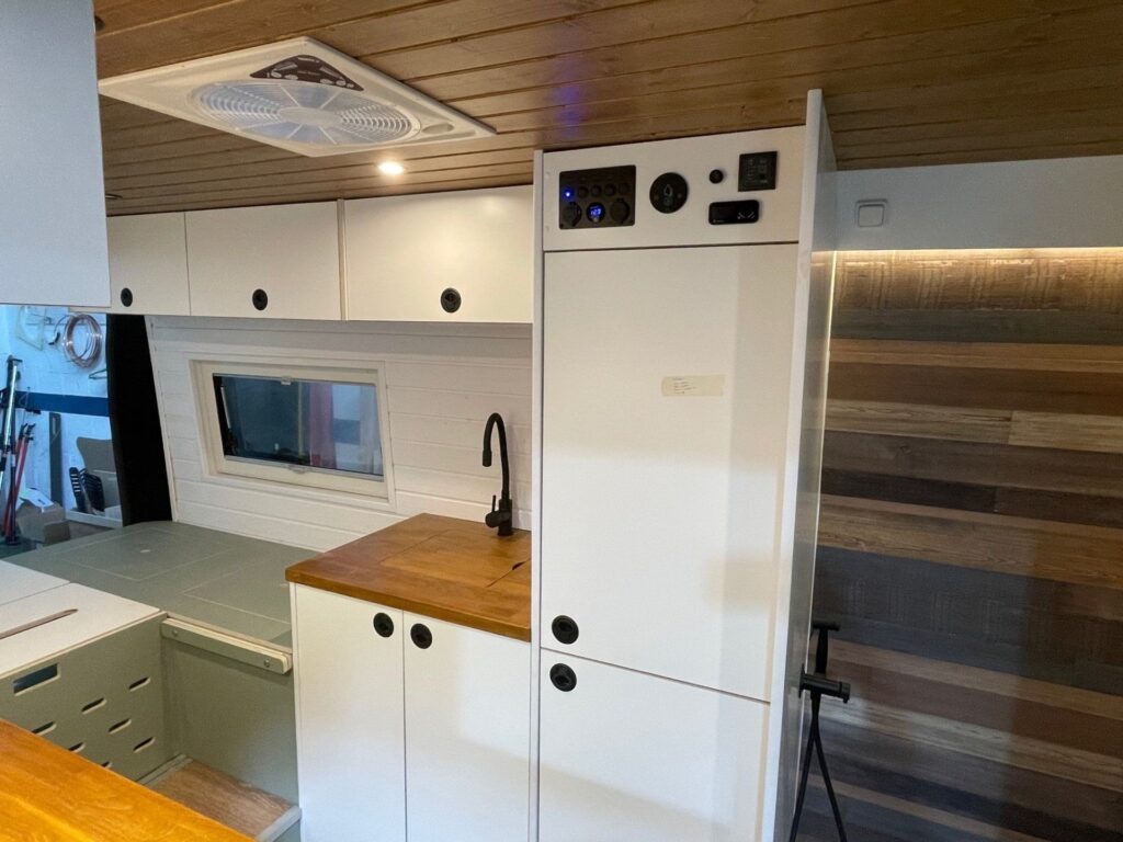Peugeot Boxer L3H2 2+2 camper vista desde el interior, destacando la cocina con encimera y el espacio de almacenamiento.