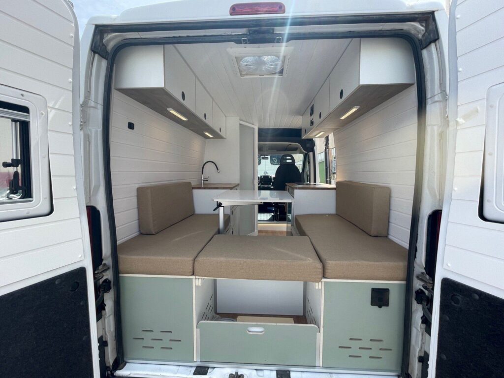 Interior personalizado de la Fiat Ducato L2H2 por Baovan Camper, con espacio para comer y almacenamiento inteligente para dos.
