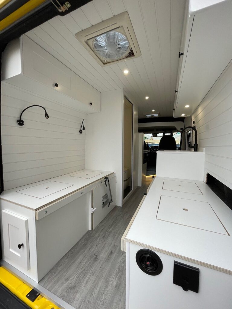 Detalle de la cocina con fregadero, estufa y acabado blanco elegante en la Peugeot Boxer L3H2 4+2 CORIAN, Camperización por Baovan Camper.