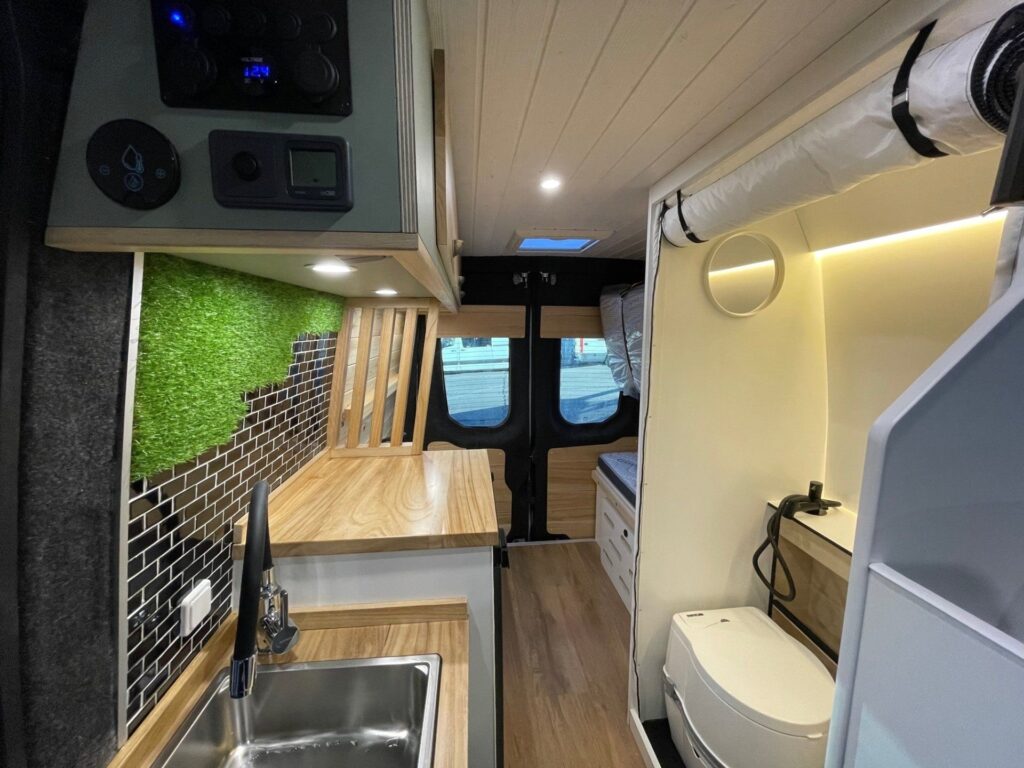 Vista de la Iveco Daily 4+4 Pawlonia: acabado blanco y amadeirado, baño completo, cocina decorada, mucho espacio. Camperizado por BaovanCamper