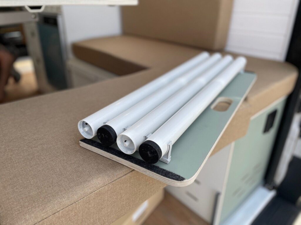 Primer plano de un conjunto de tubos de luz LED blancos montados en una mesa plegable dentro de una Fiat Ducato L2H2 camperizada por Baovan Camper, destacando el diseño inteligente y la funcionalidad que aporta la empresa en la personalización de vehículos recreativos.