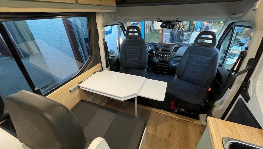 Detalle de la zona de descanso: asientos delanteros girados 180 grados, espacio para 4 personas, mesa extensible. Camperizado por BaovanCamper