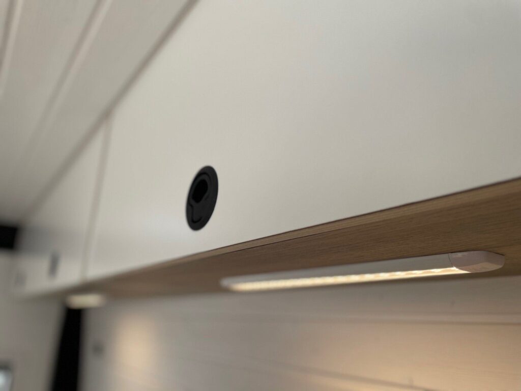 Detalles del armario y la iluminación inteligente en la Camper Fiat Ducato L2H2 para 2, convertida por Baovan Camper. Armario blanco con iluminación integrada