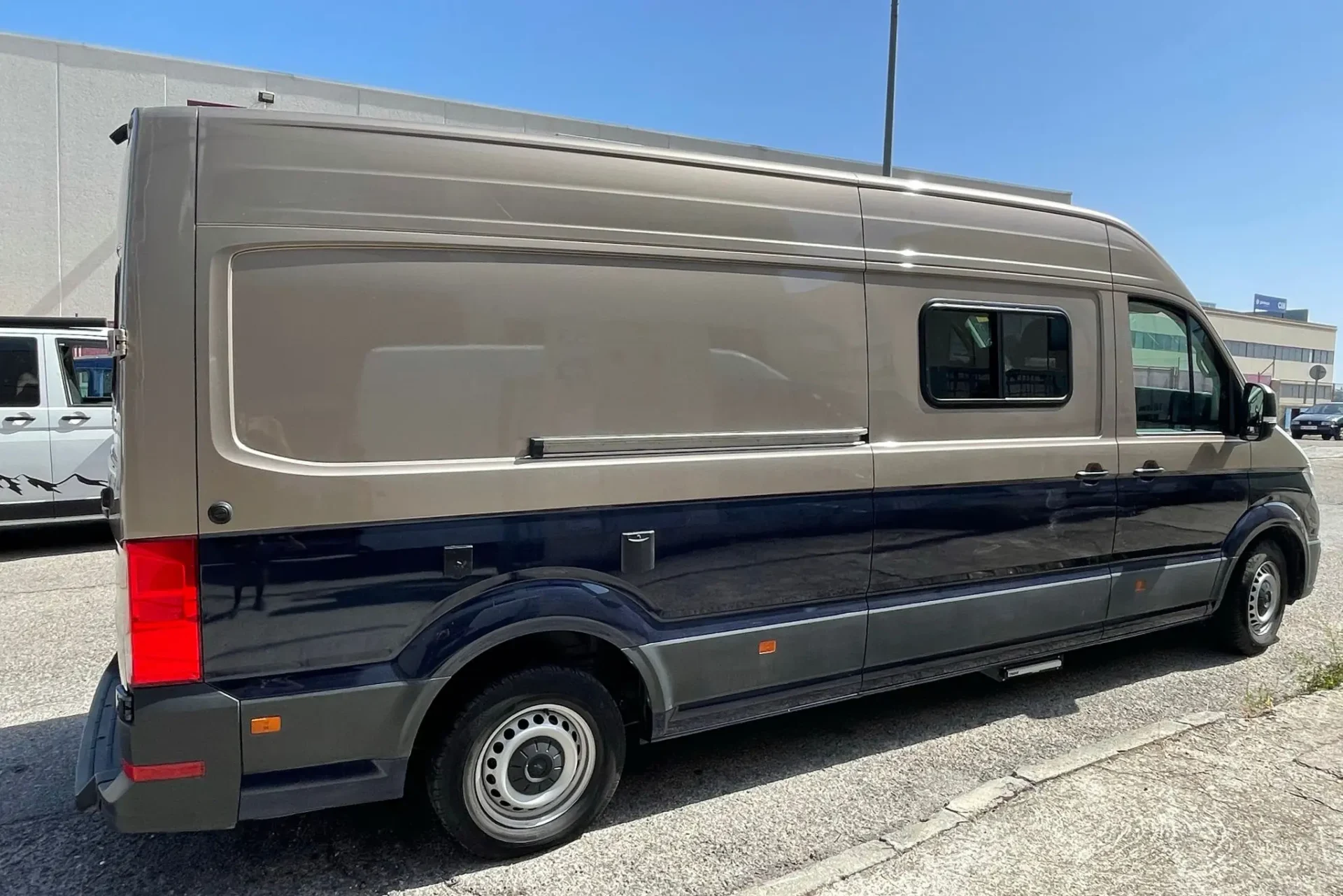 Camper VW Crafter L4H2 gris y azul aparcada y cerrada.