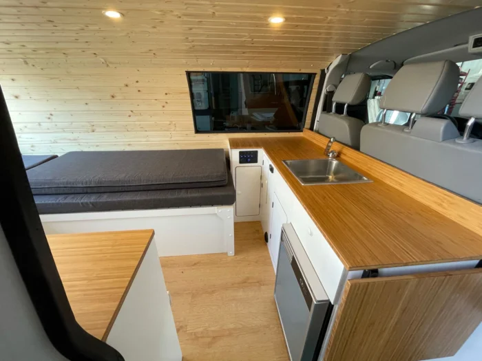 Detalles de la encimera con gran espacio de trabajo y la cama de la VW T6 Camper. Cuando está recogida funciona como sofá, ocupando una parte como cama individual.