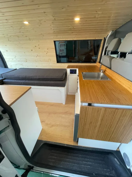 VW T6 Camper con detalles de la encimera: amplia y versátil, cama plegable, funciona como sofá individual, materiales de alta calidad, diseño compacto y funcional.
