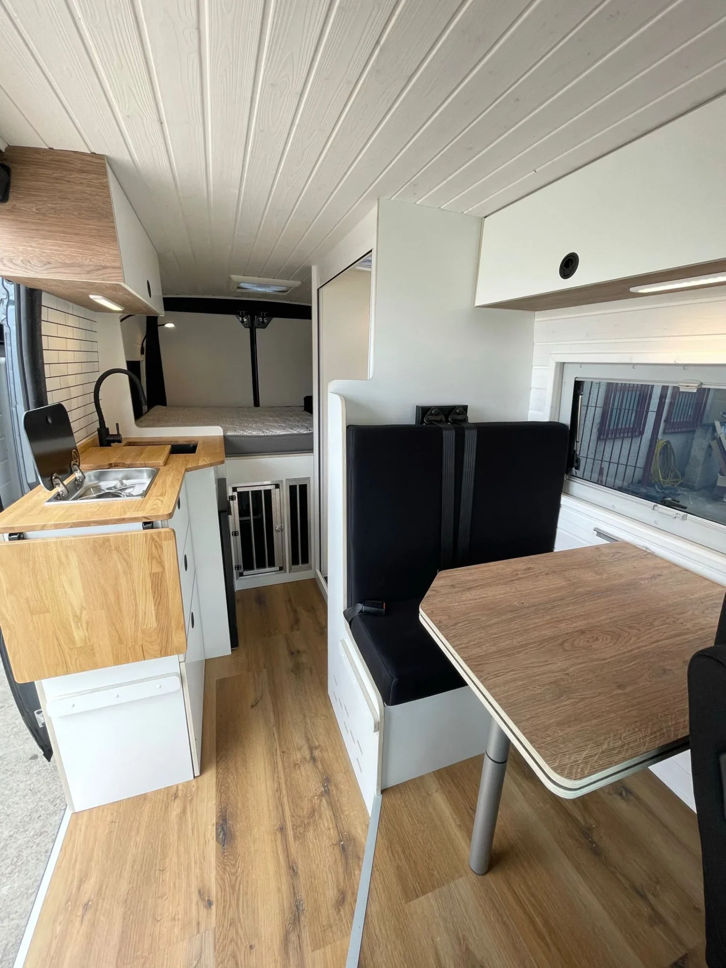 Interior de la camper con mesa plegable, fregadero y cama