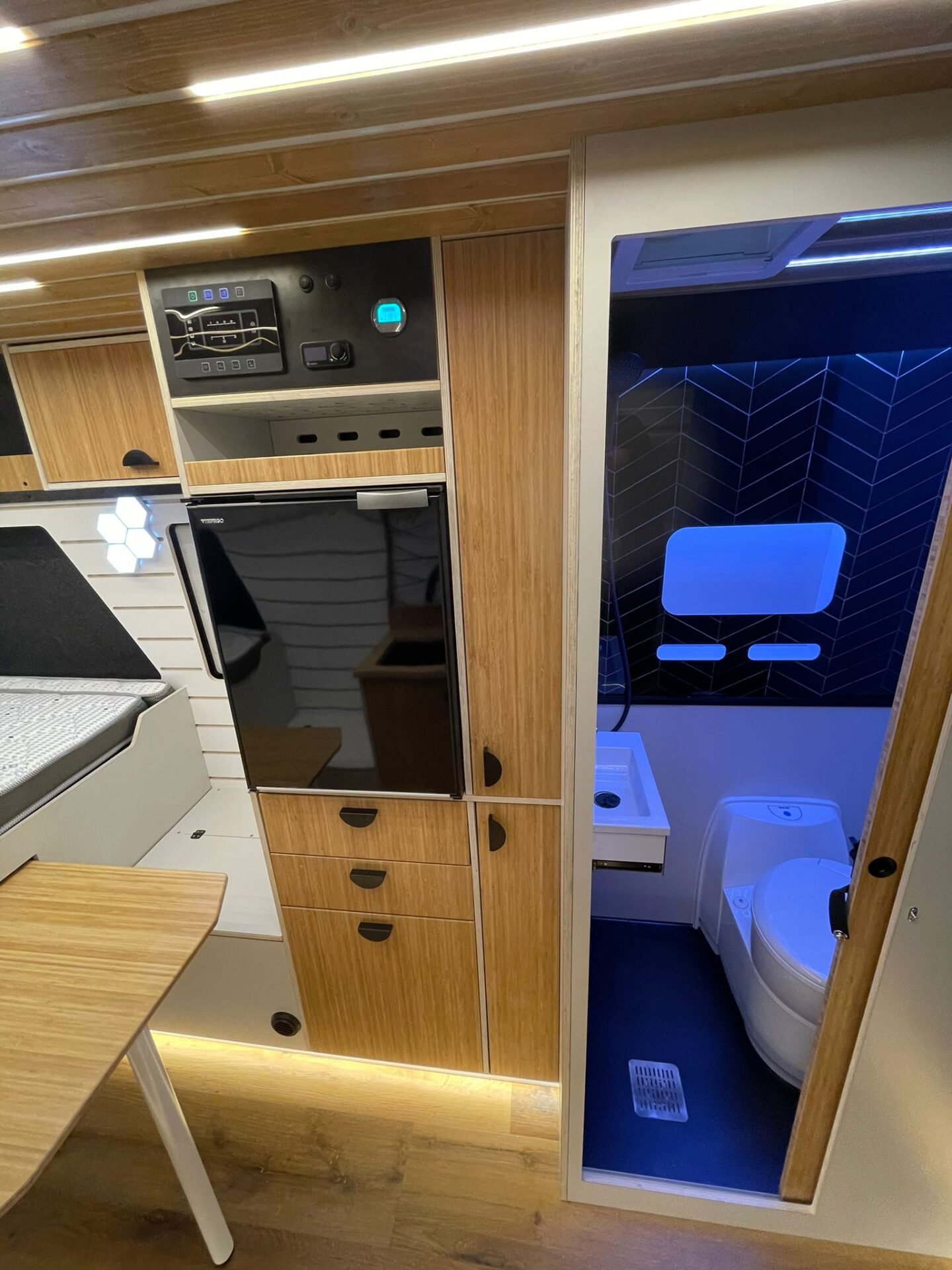 Baño completo con inodoro moderno, nevera y espacio de almacenamiento.