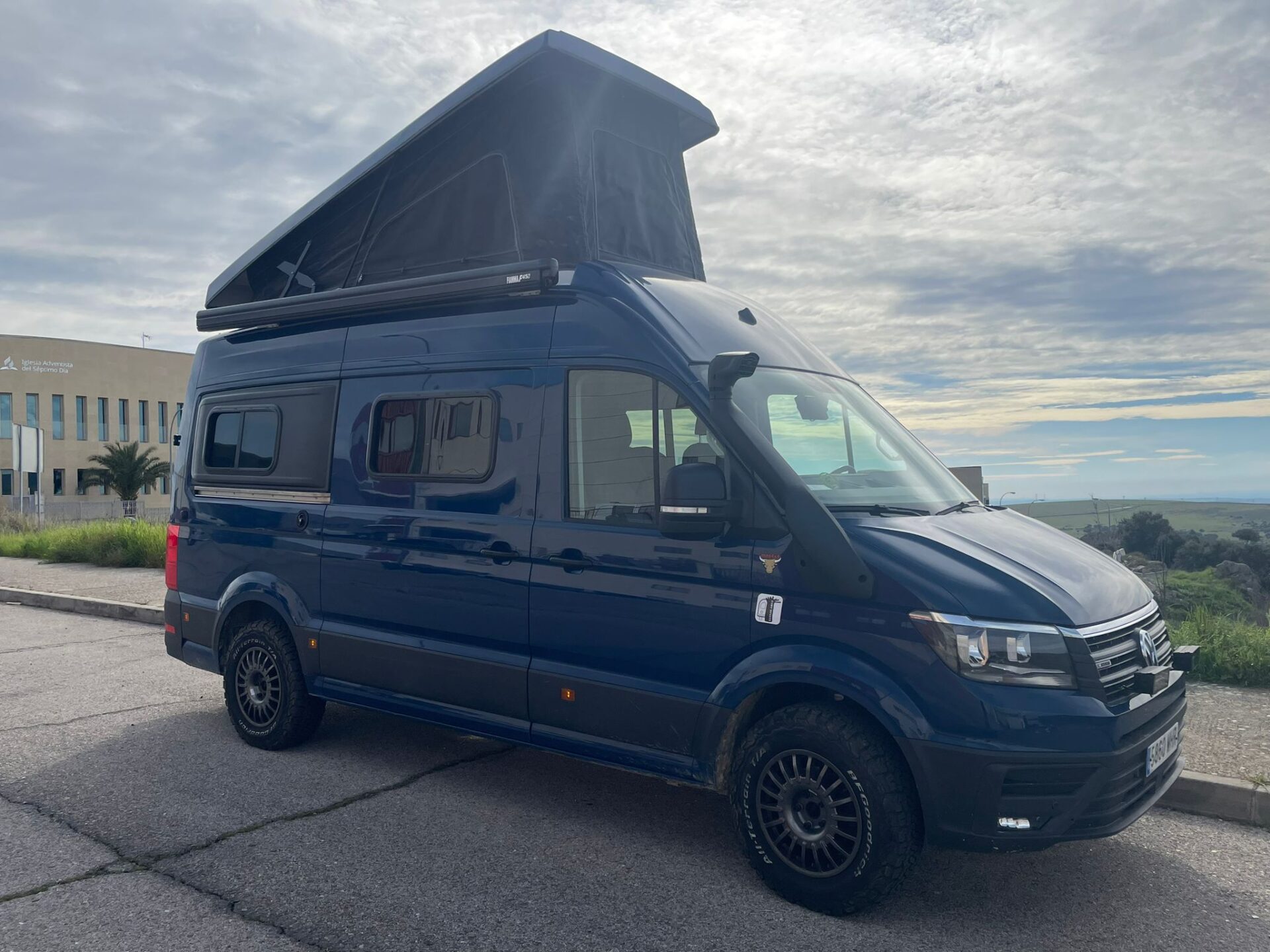 Camper Baovan azul con techo elevable en un entorno natural, destacando su diseño robusto y su preparación para la aventura.